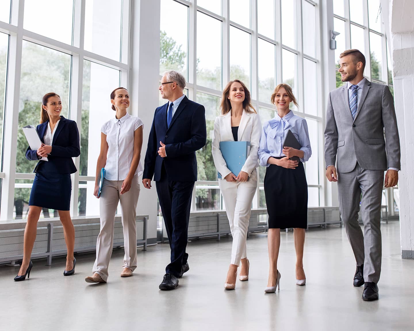 business team with folders walking along office building and talking